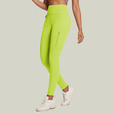 A person wearing bright lime green fleece-lined leggings with side pockets and white sneakers.