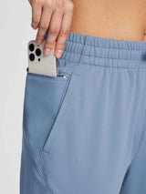 Women's blue fleece joggers with drawstring, zippered pocket holds smartphone. #color_Light Blue