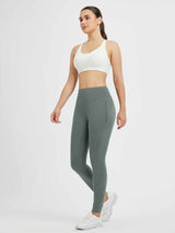 Woman wearing grey fleece-lined leggings with zippered pockets and white sneakers, side view, for cycling. #color_Dark Gray