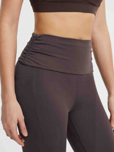 Close-up of dark gray yoga pants with a ruched fold-over waistband and side pocket. #Color_Seal Brown