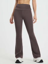Women wearing dark gray yoga flared pants with a fold-over waistband and white sneakers. #Color_Seal Brown