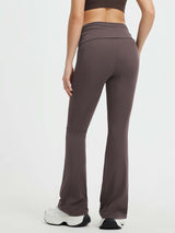 Woman wearing dark gray yoga fold-over waistband high-waisted flared pants with side pockets. #Color_Seal Brown