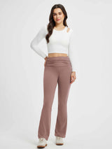 Woman wearing high-waisted flared yoga pants in a dusty rose color with a white long-sleeve crop top. #Color_Brown