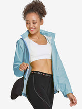 Woman in light blue waterproof cycling rain jacket and black leggings, holding a black packable pouch. #color_Blue