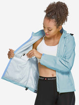 Woman places phone in pocket of blue waterproof cycling rain jacket #color_Blue