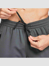 Man adjusting drawstring on men's knit fleece cycling pants in dark gray #color_Gray/Black