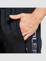 Close-up of a man's hand in the zippered pocket of black men's knit fleece cycling pants with white logo detail. #color_Black