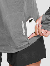 Women's gray UPF 50+ hiking shirt with a phone placed in the zippered pocket, showing the Baleaf logo. #color_Dark Gray