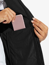 Woman placing phone in zippered pocket of black women's windproof softshell vest #color_Black