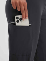 Women's dark grey capri pants featuring a zippered thigh pocket holding smartphone, reflective stripe detail. #color_Black