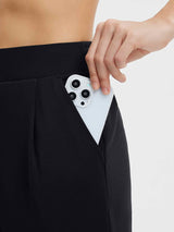 Black golf pleated fleece slim-fit pants with a hand placing a smartphone into the pocket. #color_Black