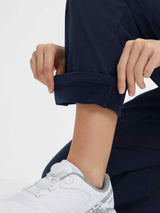 Navy blue golf pants with fleece lining being cuffed by hands, paired with white athletic shoes. #color_Navy Blue