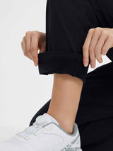 Black fleece-lined golf pants with cuffed hem and white athletic golf shoe. #color_Black