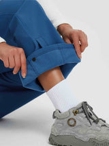 Woman's blue softshell pants with fleece lining and zipper pocket detail. Worn with socks and boots. #color_Cobalt Blue