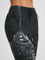Water beading off black women's softshell outdoor pants with zipper pockets. #color_Black
