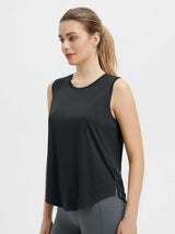 Black sleeveless racerback running tank top with curved hem and side slits, paired with grey leggings. #color_Black