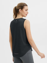 Black sleeveless racerback running tank top with reflective detail, worn by woman. #color_Black