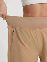Women's tan 9" high-waisted running shorts with elastic waistband and side zipper pocket #color_Brown