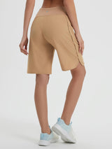 Woman's tan 9-inch high-waisted running shorts with curved hem and zippered pockets, paired with athletic shoes. #color_Brown