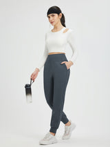 Woman in white long-sleeve top and charcoal gray fleece-lined joggers holds a water bottle. #color_Charcoal Gray