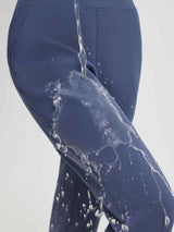 Water splashing on women's blue thermal fleece running pants, showcasing water-resistant fabric. #color_Navy Blue
