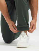 Man in dark green fleece-lined running pants adjusting the cuff to reveal thermal lining. #color_Army Green