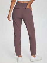 Woman wearing brown Sculpt High-Waist Tapered Yoga Pants with pockets and white sneakers. #color_Dark Brown