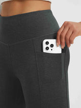 Woman's hand placing a phone into a side pocket of heather dark gray floral fleece yoga pants. #color_Black