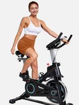 Woman cycling in brown V-waist cycling shorts and white sports bra #color_Brown