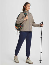 Woman in navy blue fleece jogger pants, equipped for hiking with poles and backpack. #color_Navy Blue