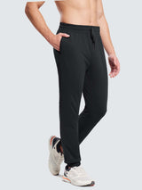 Men's black fleece jogger pants with zippered pocket and reflective accents, paired with white athletic shoes. #color_Black