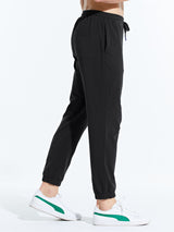 Men's black cotton joggers with elastic waistband and cuffed ankles, paired with white sneakers. #color_Black/Blue