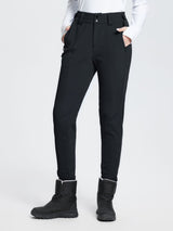 Black stretch knit slim-fit ski pants with zippered pockets and fuzzy ankle trim, worn with snow boots. #color_Black