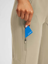 Woman's hand placing blue Baleaf card into zippered pocket on khaki UPF capris for outdoor wear. #color_Doeskin