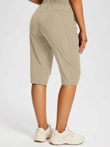 Khaki UPF50+ DWR pocketed capris with elastic waistband and beige sneakers for outdoor wear. #color_Doeskin