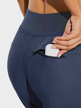 Navy women's hiking joggers with zippered pocket holding an earbud case #color_Navy Blue