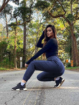 Woman in tall high-waisted quick-dry hiking joggers squatting on a road in a forest. #color_Navy Blue