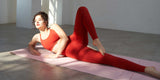 Woman doing yoga stretch in red leggings and sports bra on mat
