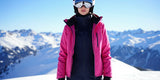 Stylish woman wearing two-piece ski bibs and jacket on a snowy mountain peak, showcasing best ski suits 2026.