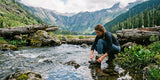 Hikers wearing quick-drying fleece-lined camping pants leggings near mountain stream with outdoor gear