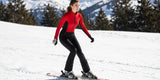 A woman in a red and black ski suit skis down a snowy mountain.