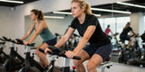 Woman wearing moisture wicking shirts and padded bike shorts during intense indoor cycling class