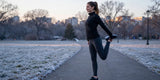 Woman wearing fleece lined leggings stretching before winter morning run in frosty park