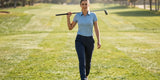 Female golfer wearing stylish golf joggers women love, walking confidently on a sunny fairway