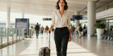 Happy woman pulling carry-on luggage wearing comfortable lightweight women's travel pants in an airport