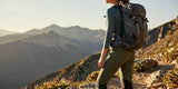 Woman wearing the best hiking pants for women looking at mountain sunrise on trail