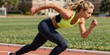 Fit Caucasian woman wearing performance sport clothes sprinting on an outdoor running track.