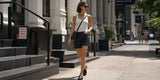 Woman wearing navy cargo shorts and a white tank top on a city sidewalk
