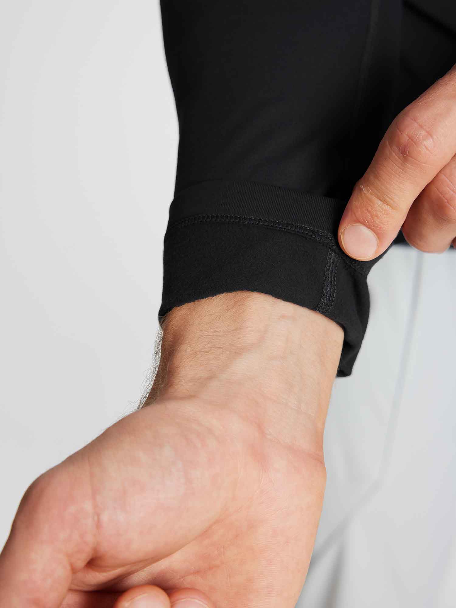 Close-up of a man's hand showing the fleece-lined cuff of a black Men's Half-Mock Knit Fleece Running Top. #color_Black