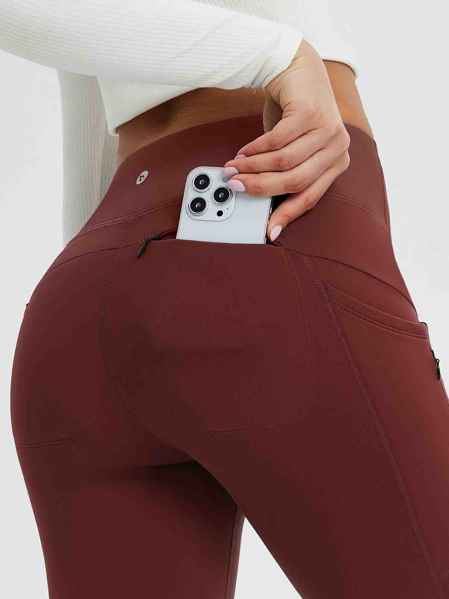 Close-up of wine red fleece-lined yoga leggings showing a phone being placed in a side pocket. #color_Wine Red